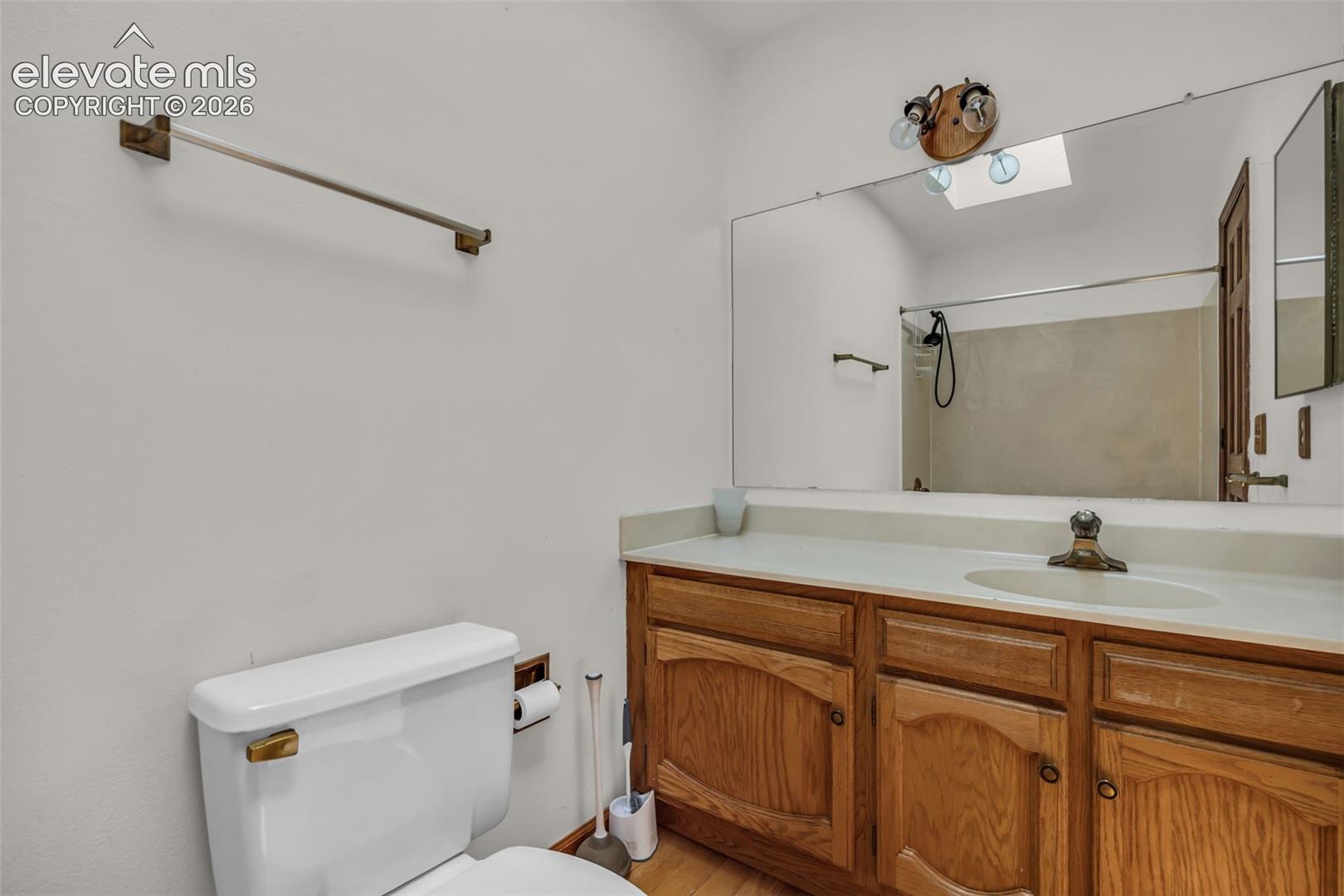 Bathroom with oak vanity, broad mirror, and walk-in shower.