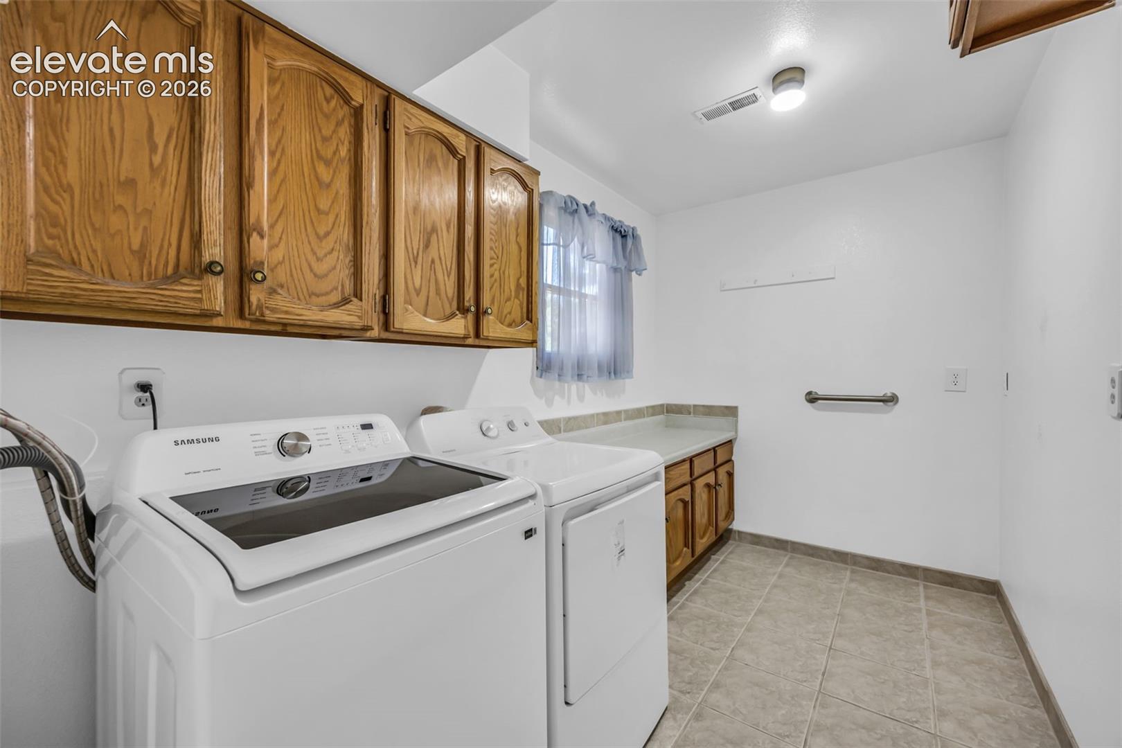 Laundry room with washer and dryer, wood cabinets, and a folding counter.
