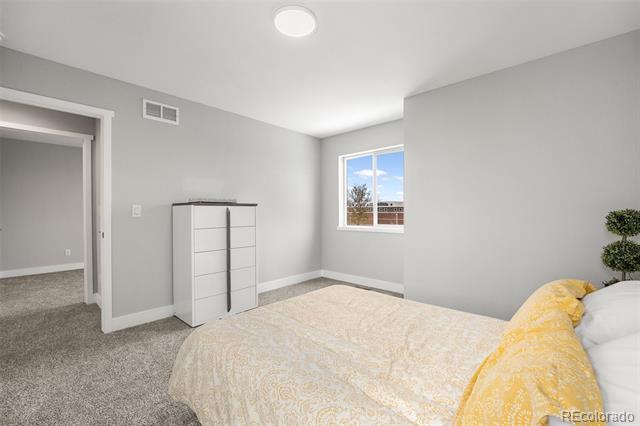 Bedroom with gray walls, carpet, white dresser, and a bed with a yellow patterned blanket.