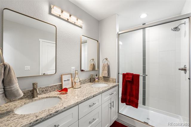 Bathroom with double vanity and glass shower; a red towel hangs over the shower door.