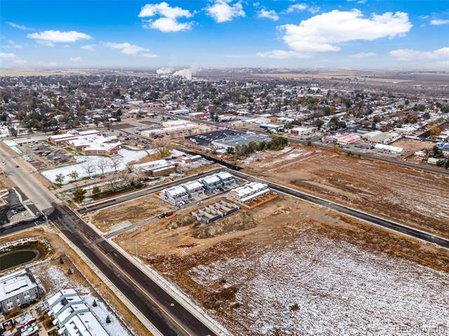 Aerial view of vacant land beside a road, with nearby homes and town development.