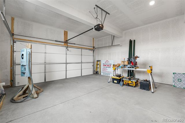 Spacious garage with a concrete floor, closed overhead door, and workshop tools.