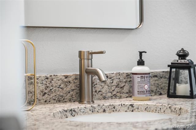 Bathroom sink with a brushed metal faucet, speckled granite counter, soap dispenser, and black lantern.