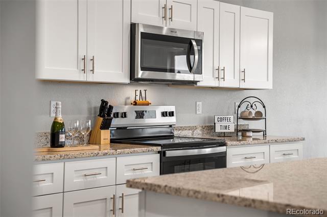 Kitchen with white cabinets, granite counters, stainless steel appliances, and a small coffee station.