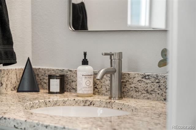 Bathroom vanity with a speckled stone counter, white sink, and brushed-metal faucet.