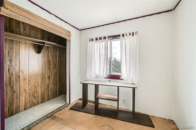 Small room with a wood-paneled open closet and a narrow table beneath a curtained window.