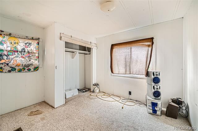 Carpeted bedroom with an open closet, shaded window, and floor-standing stereo.