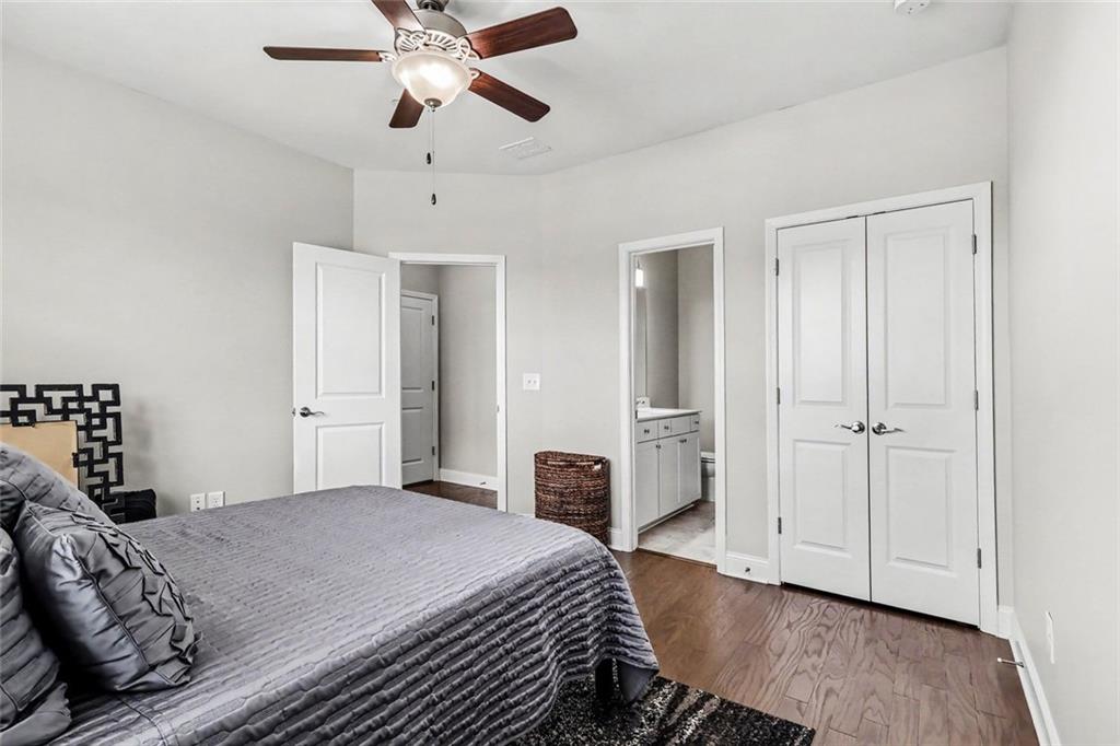 Bedroom with a gray quilted bed, ceiling fan, and open view to a bathroom vanity.