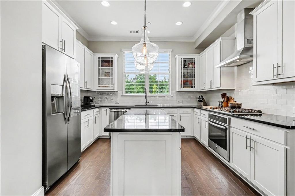 Kitchen with white cabinets, stainless steel appliances, and a black-topped island.