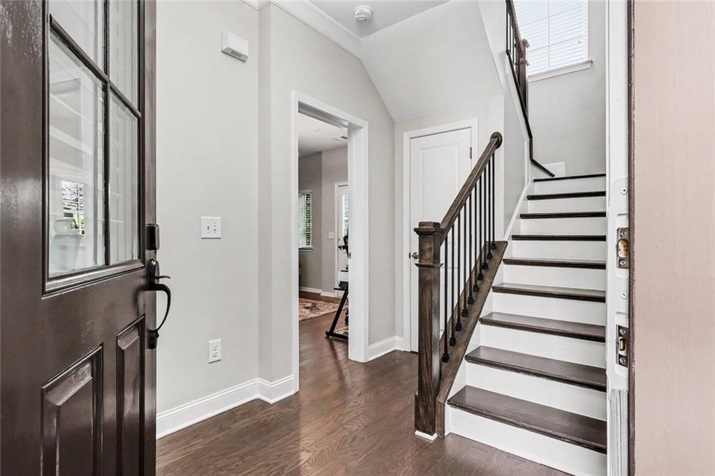 Entry foyer with a dark wood staircase, hardwood floors, and a tall window.