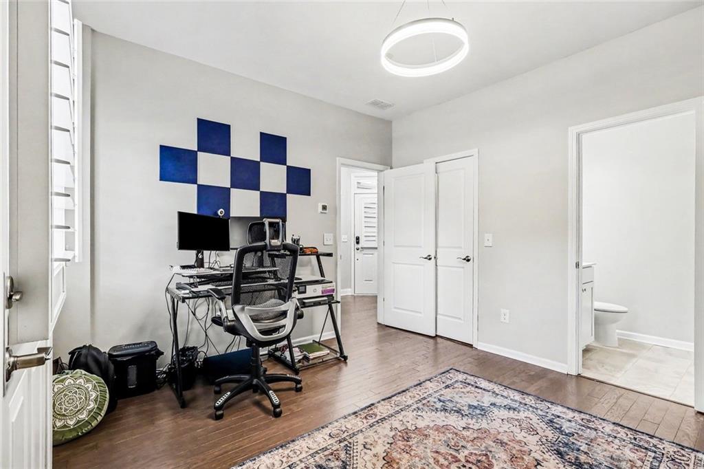 Home office with a computer desk, blue-and-white wall panels, and an adjoining bathroom.