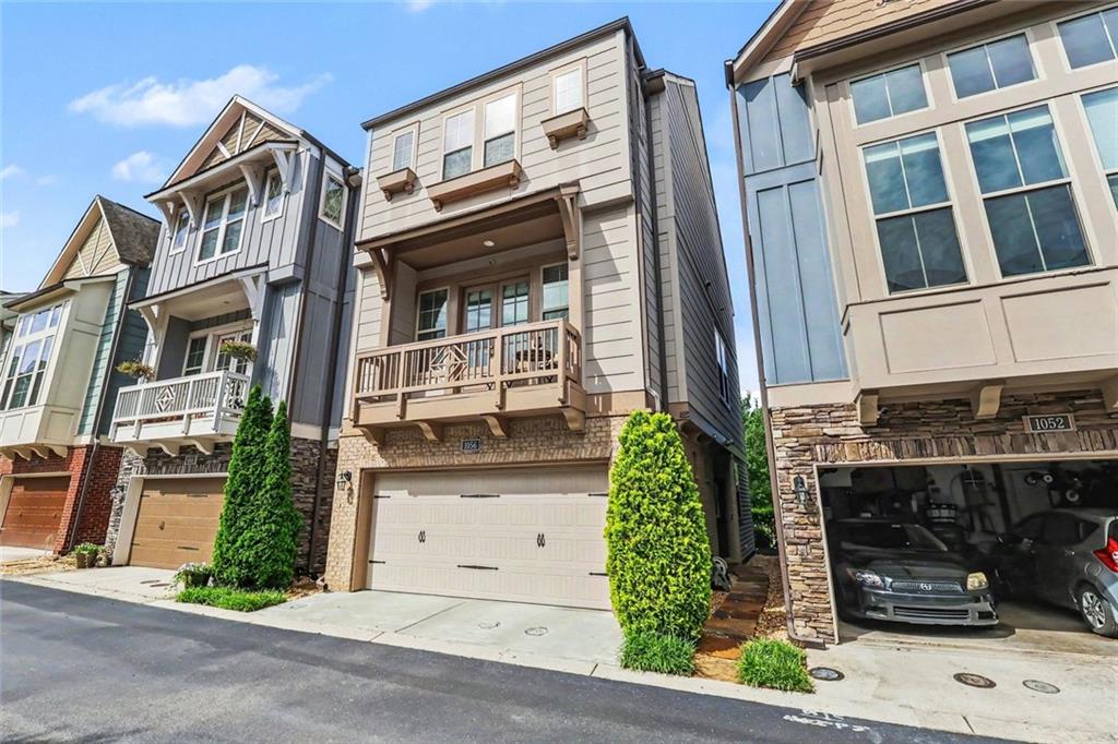 Townhouse with a covered balcony, stone-accented facade, and attached garage.