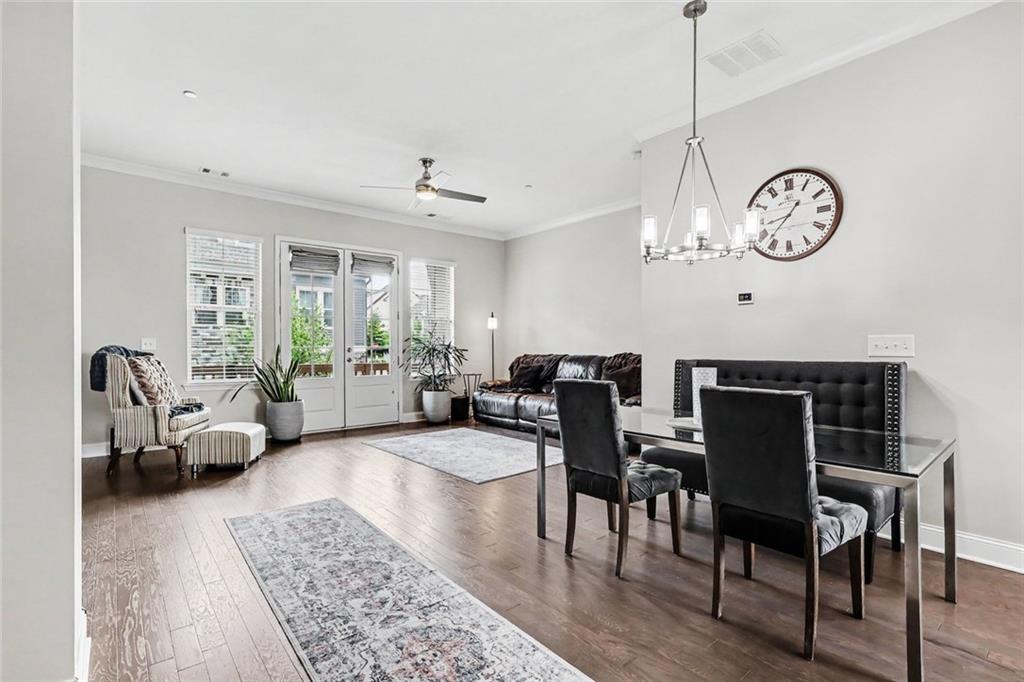 Open living and dining room with hardwood floors, French doors, and a chandelier.