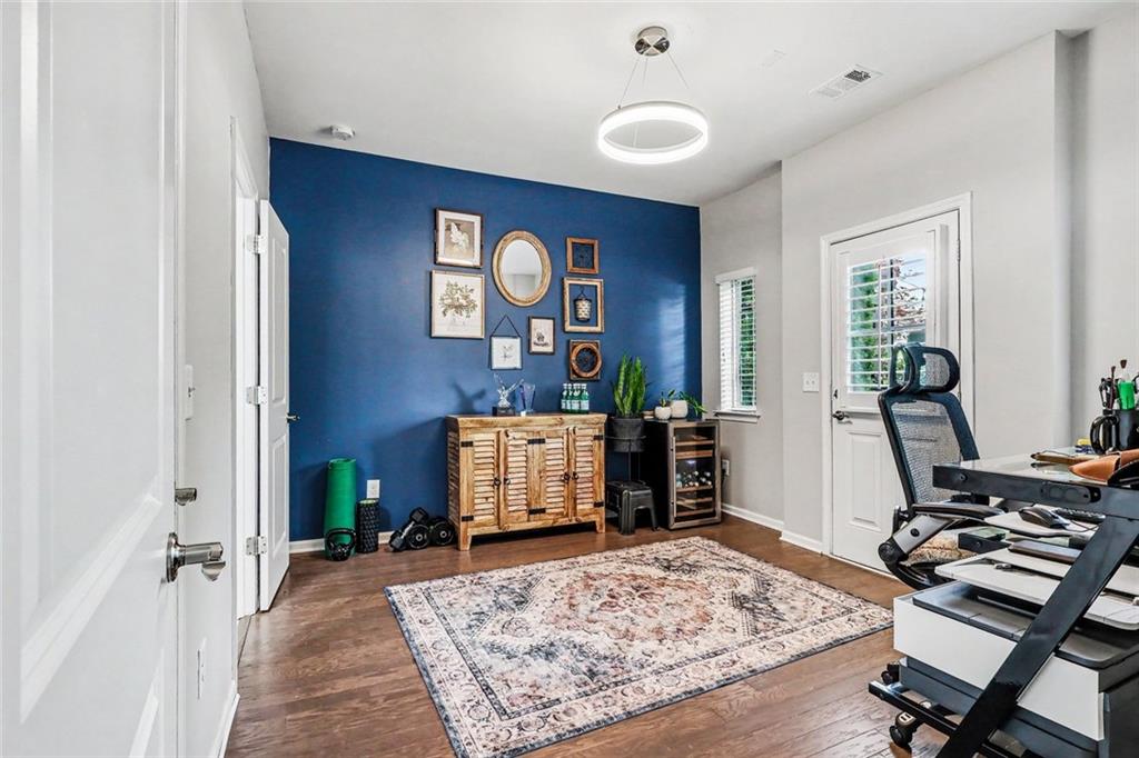 Home office with a deep blue accent wall, framed art, and patterned rug.