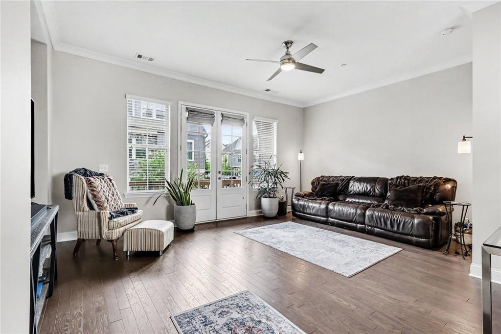 Living room with a dark leather sofa, armchair, and French doors opening to a patio.