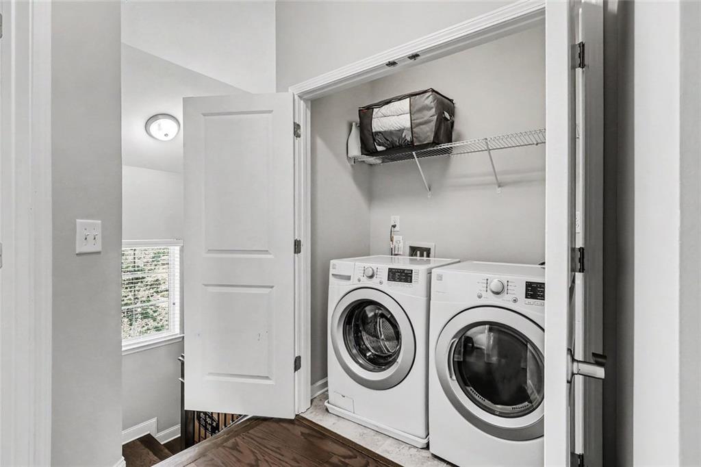 Laundry room with front-loading washer and dryer beneath a wire shelf.