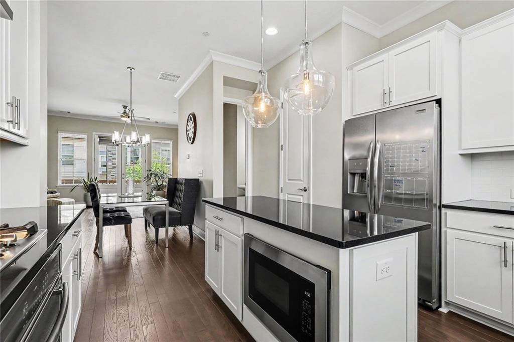 Kitchen with a black-countertop island and stainless refrigerator, opening to a dining area.