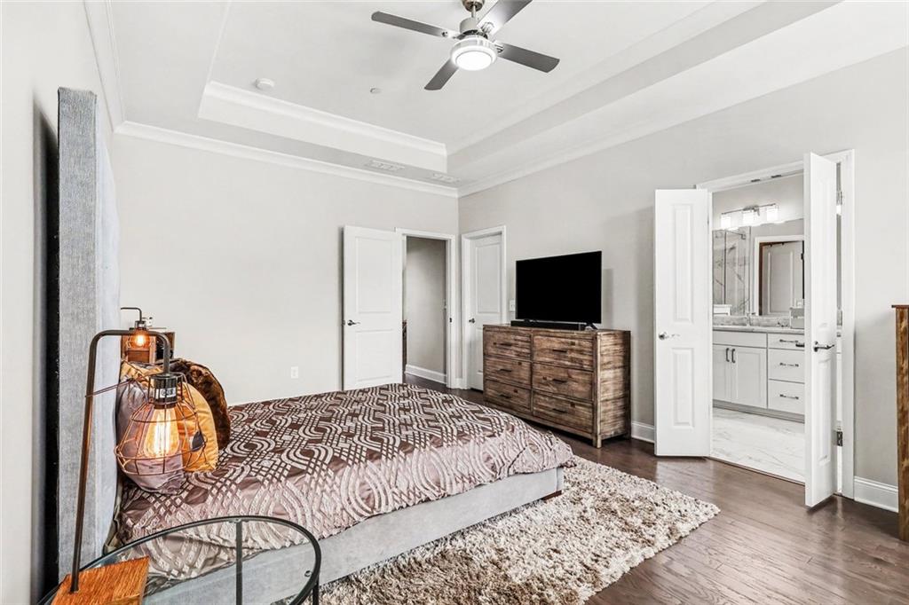 Bedroom with patterned bedding and open doors to an ensuite bathroom.