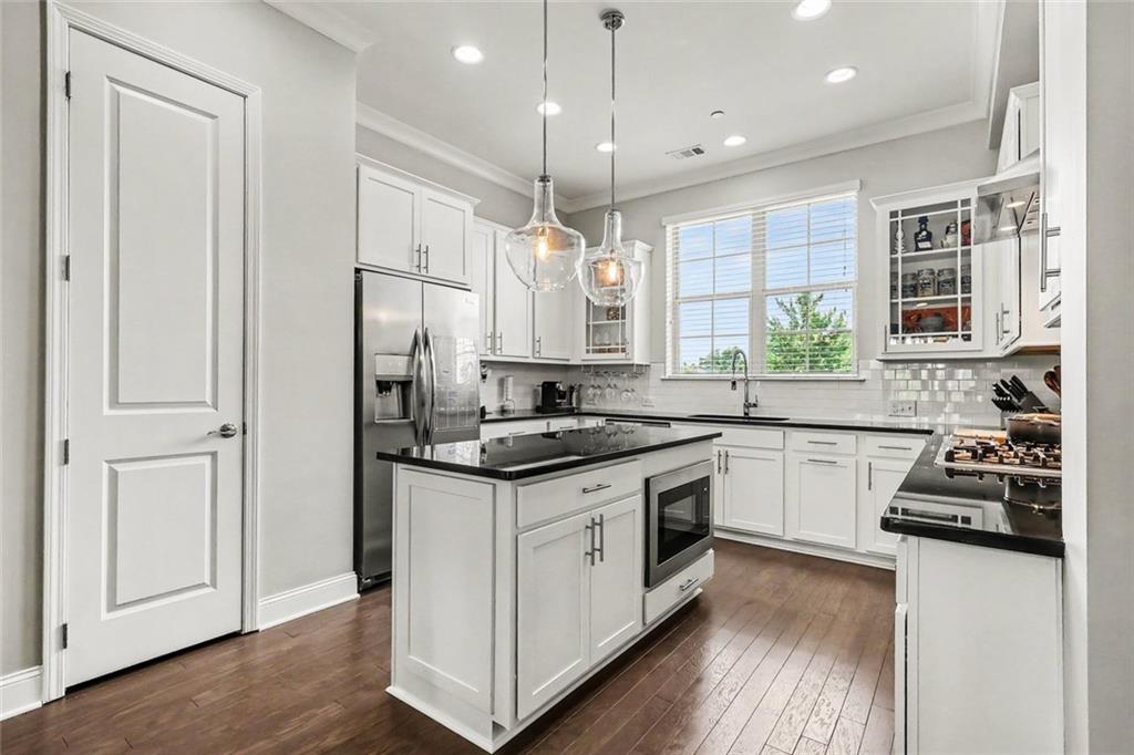 Kitchen with a central island, white cabinetry, dark countertops, and stainless steel appliances.