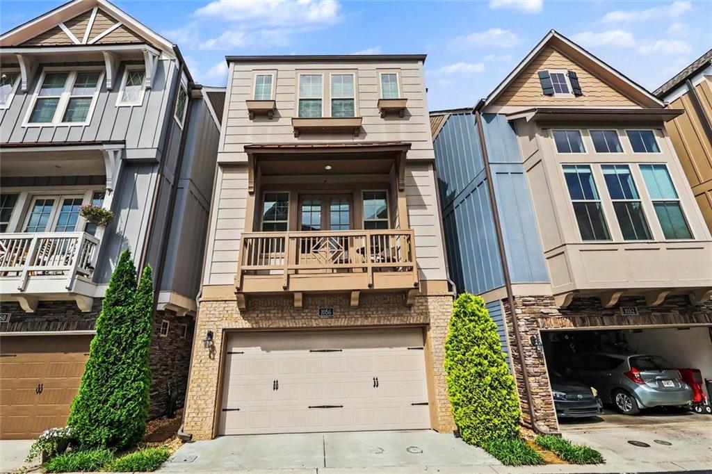 Townhouse with a stone facade, second-floor balcony, and two-car garage.
