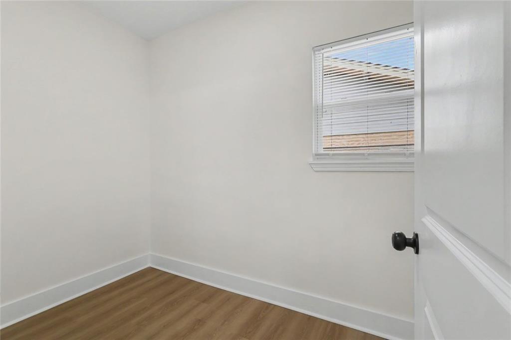 Empty bedroom with wood flooring and a window with white blinds.