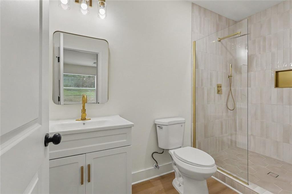 Bathroom with a white vanity and gold fixtures beside a glass-enclosed tiled shower.