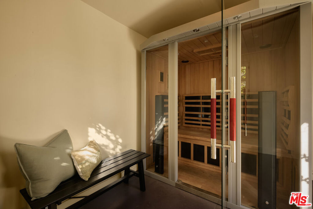 Wood-lined sauna behind glass doors, with a cushioned bench outside.