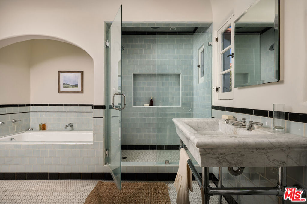 Bathroom with a glass-enclosed tiled shower, bathtub, and marble vanity.
