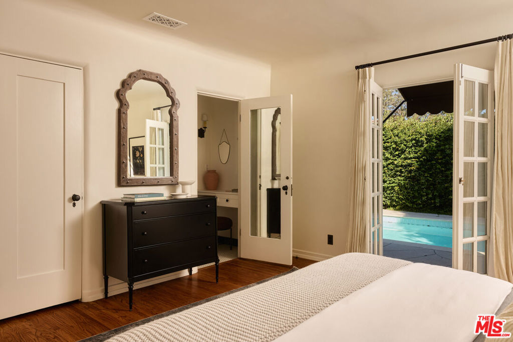 Bedroom with an ornate mirror and French doors opening to a swimming pool.