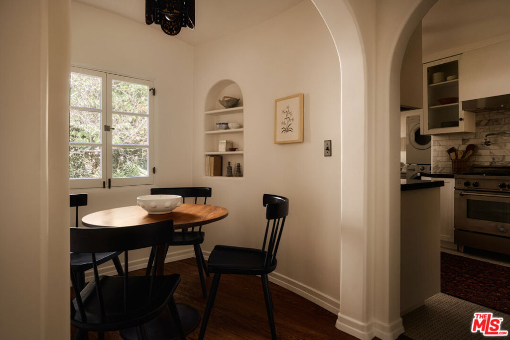 Dining nook with a round wood table, black chairs, and a built-in display niche beside a window.