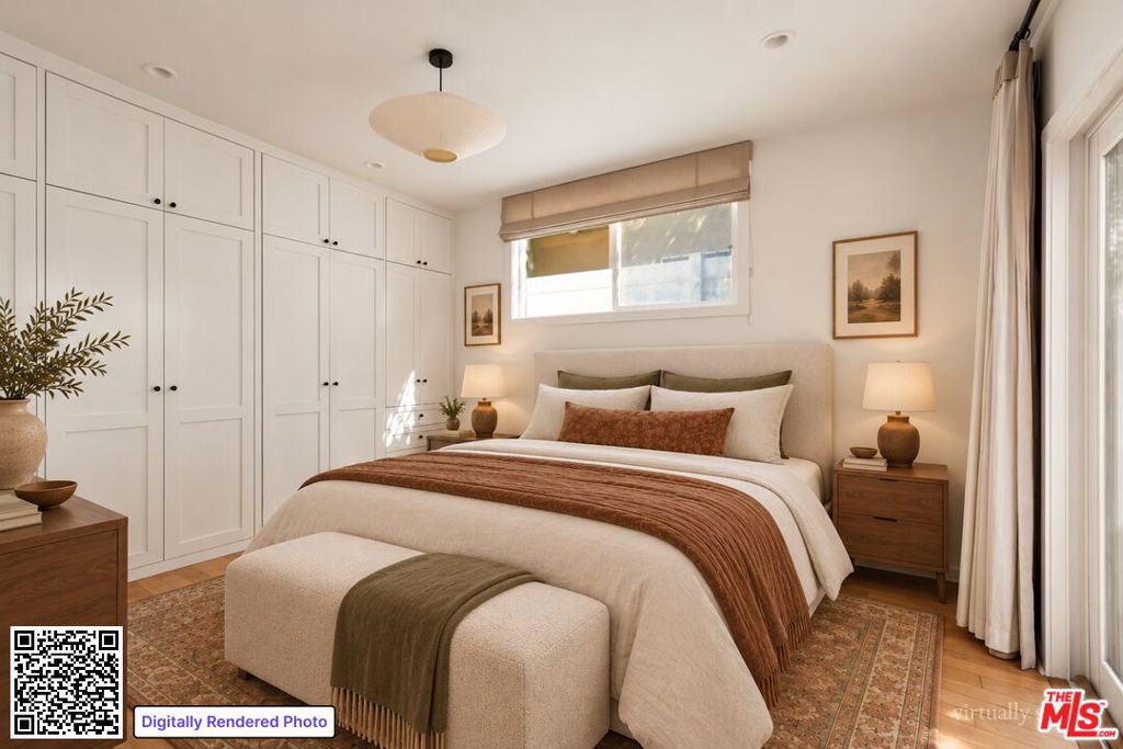 Bedroom with a large upholstered bed, white built-in wardrobes, and warm wood furnishings.