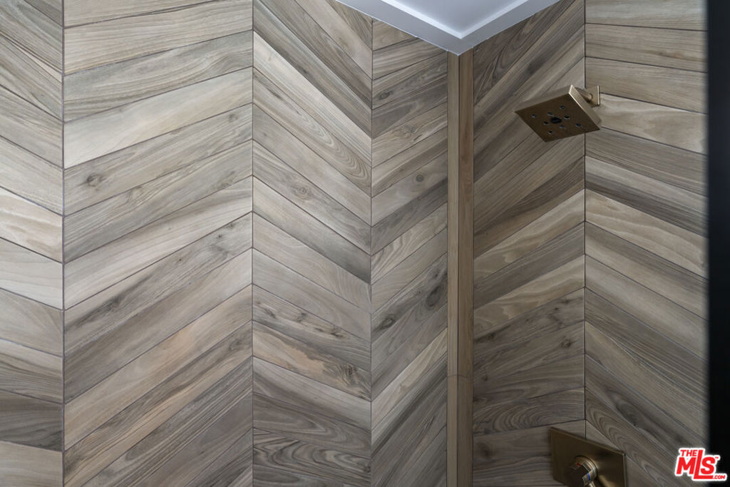 Shower with chevron-patterned wood-look tile and a square overhead showerhead.