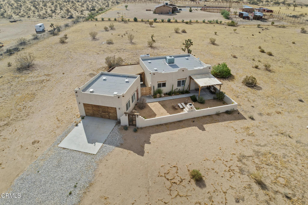 Aerial view of a flat-roof desert home with a walled courtyard, covered patio, and detached garage.