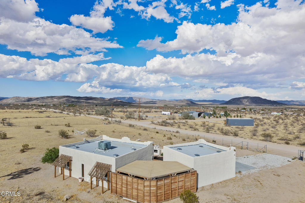 Aerial view of a desert home with a wooden fenced patio and distant mountains.