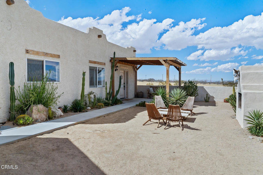 Desert home courtyard with a wooden pergola, lounge chairs, and cacti.
