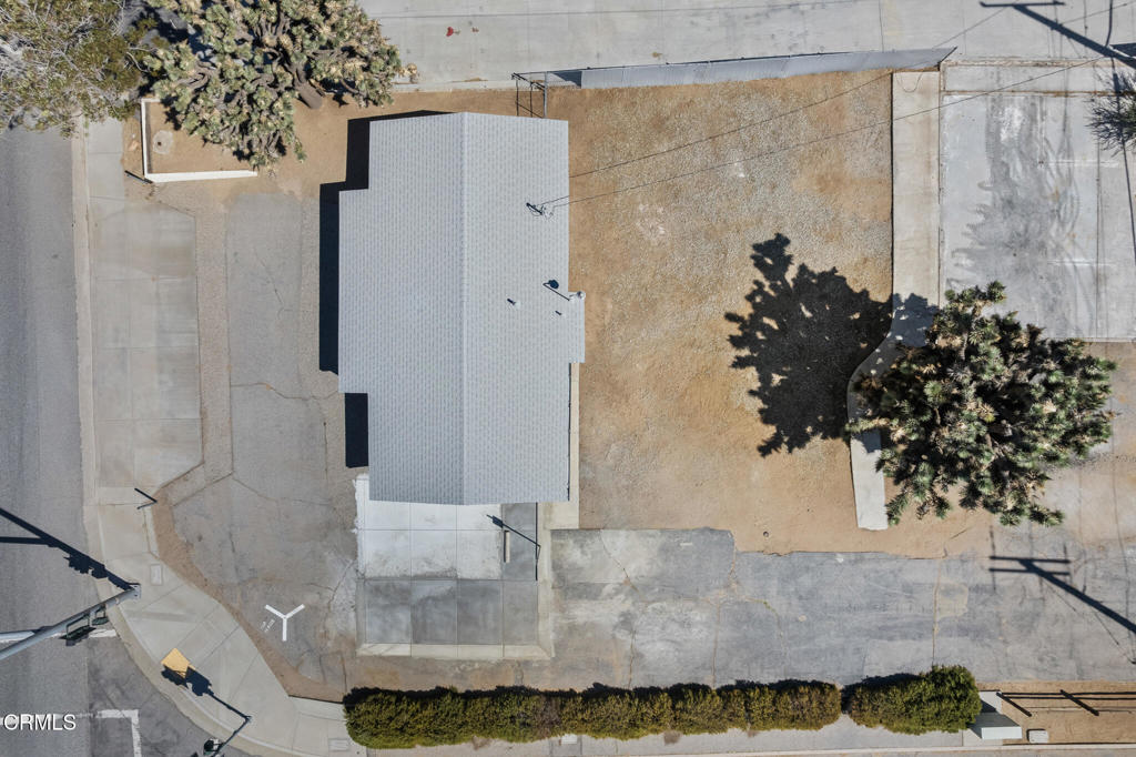 Aerial view of a single-story home, paved driveways, and a dry yard.