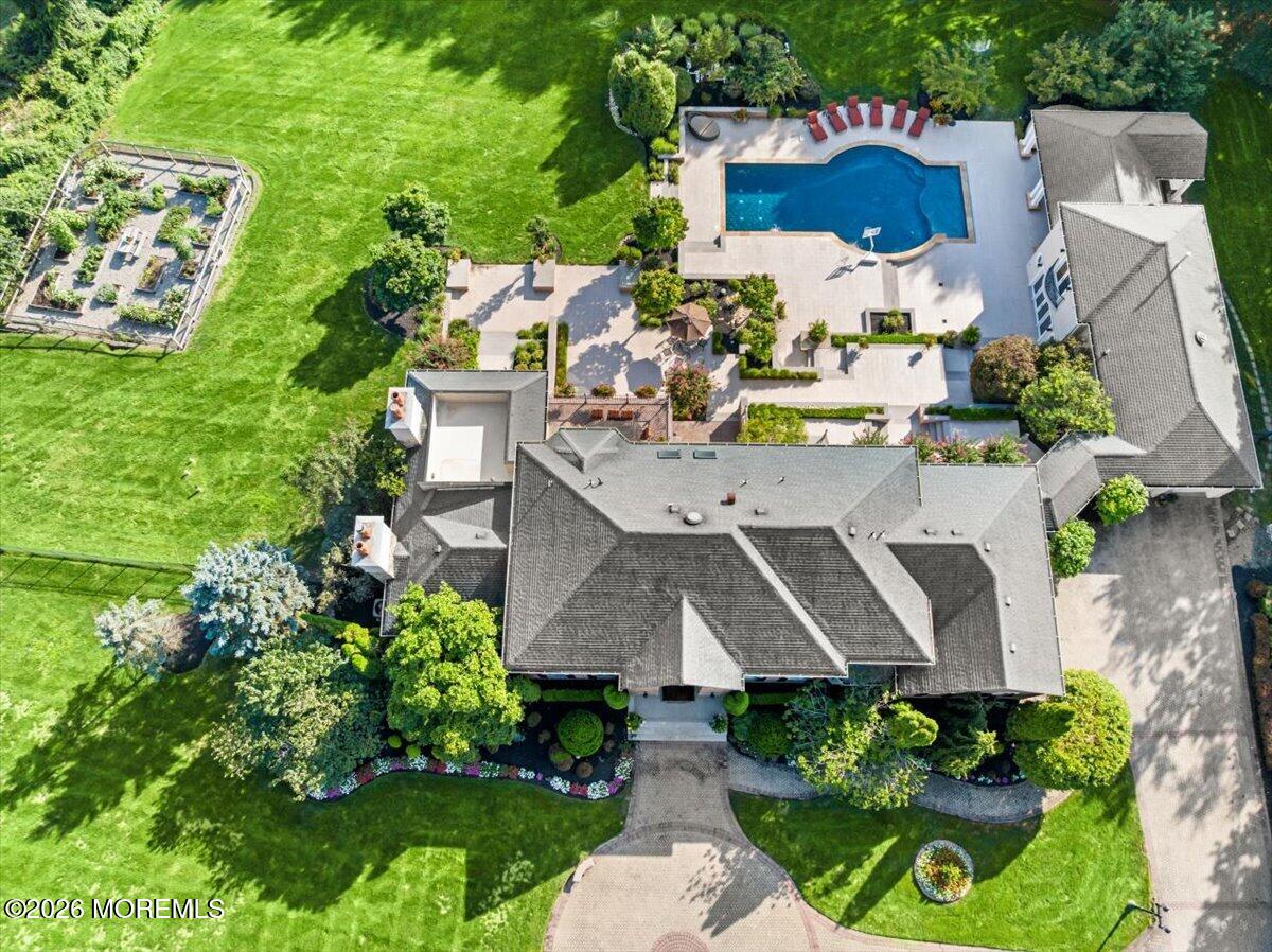 Aerial view of a large home with landscaped grounds, a swimming pool, and patio areas.