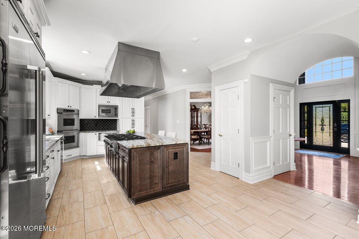 Spacious kitchen with a dark wood island, white cabinets, stainless appliances, and an arched entryway.