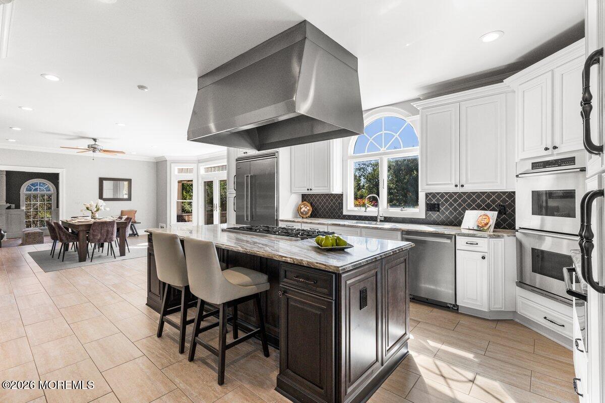 Bright kitchen with a dark wood island, white cabinets, stainless appliances, and an adjoining dining area.
