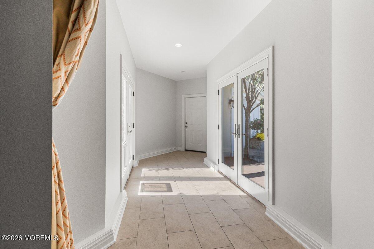 Tiled entry foyer with glass double doors opening to a landscaped patio.