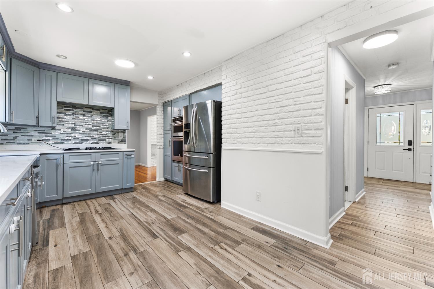 Renovated kitchen with blue-gray cabinets, stainless steel appliances, and wood-look tile flooring.