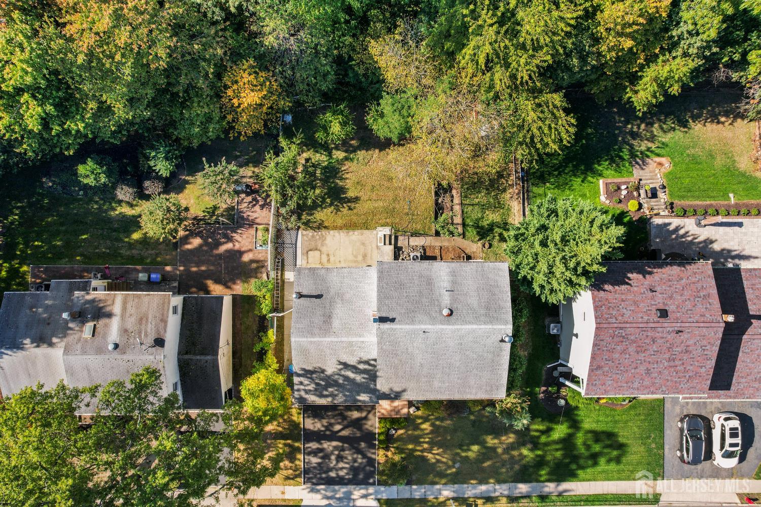 Aerial view of the home with a tree-lined backyard and paved patio.