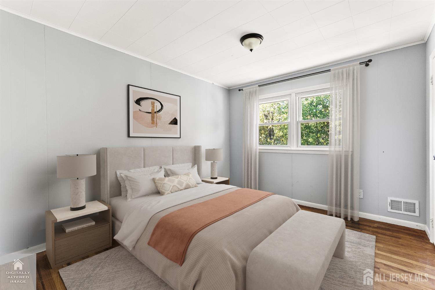 Staged bedroom with a large bed, peach throw, matching bedside lamps, and a curtained window.