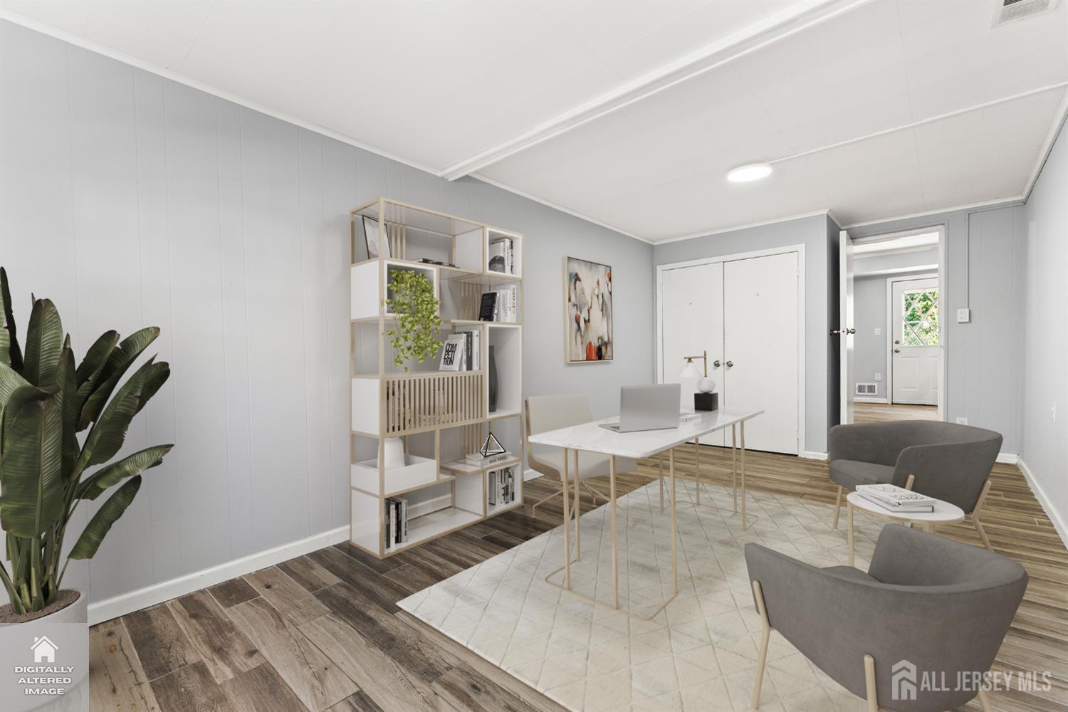 Staged home office with a white desk, laptop, open shelving, and gray lounge chairs.