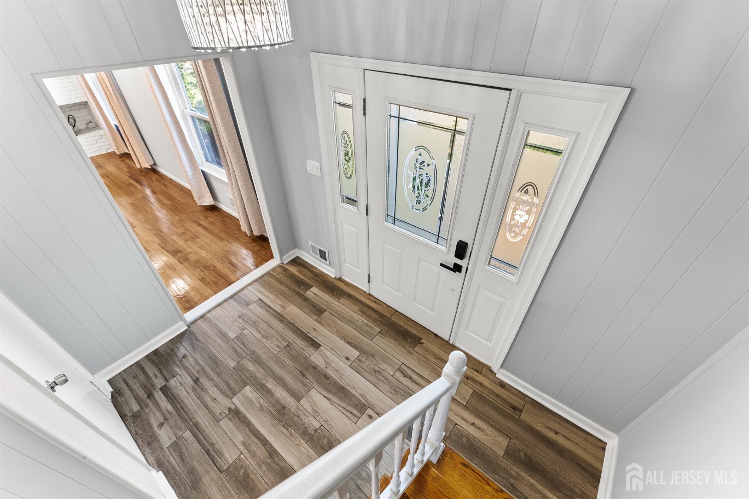 Entry foyer with a white decorative-glass front door and wood-look tile flooring.