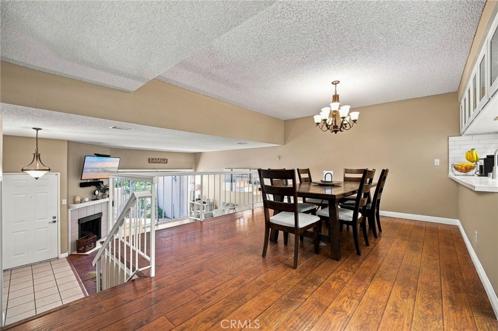 Dining area with a dark wood table, hardwood floors, and railing overlooking the living room.