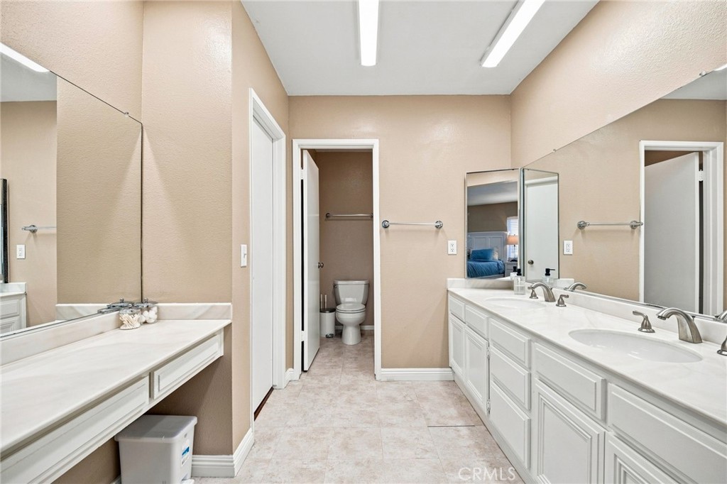 Bathroom with a long double-sink vanity, large mirrors, and a separate toilet room.