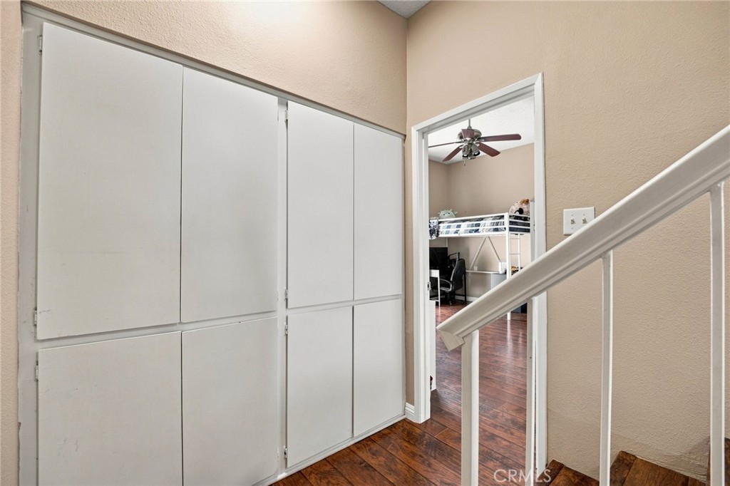 Hallway with large built-in cabinets and a staircase, opening to a bedroom with a loft bed.