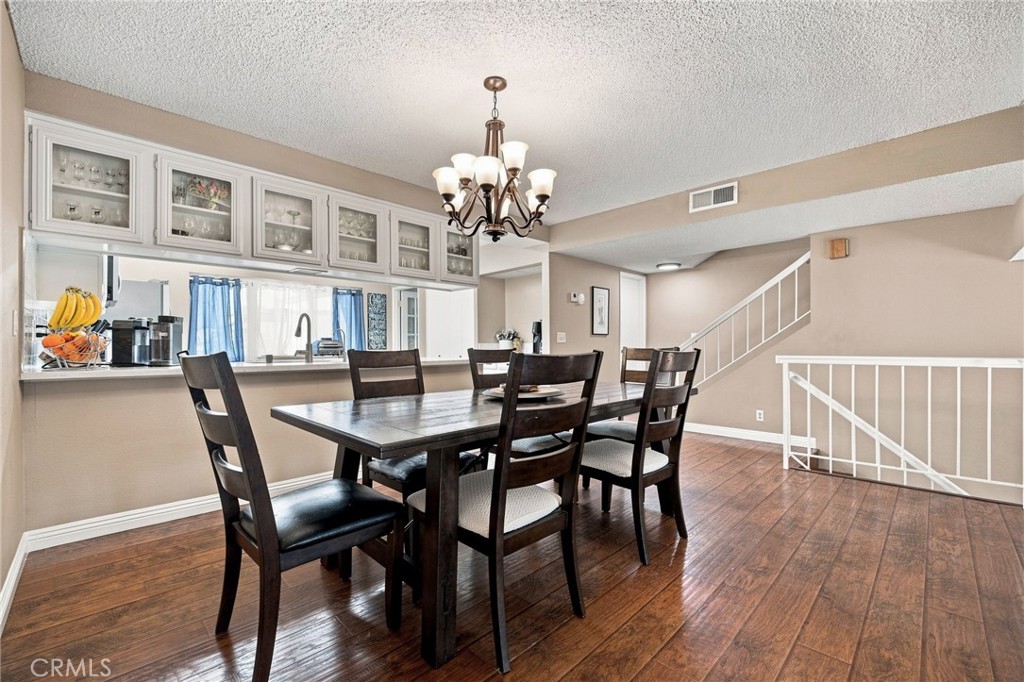 Dining area with a dark wood table, chandelier, kitchen pass-through, and staircase.