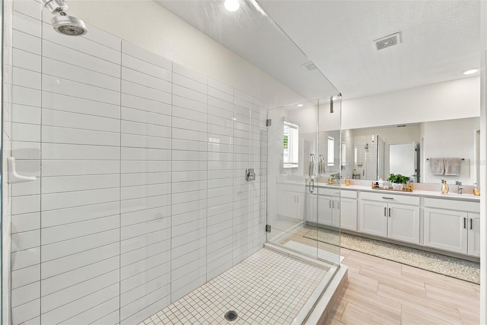 Bathroom with a tiled walk-in shower and long double vanity.